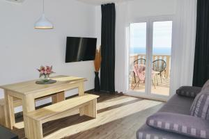 ein Wohnzimmer mit einem Sofa, einem TV und einem Balkon in der Unterkunft Marojica Apartments 2 in Cavtat