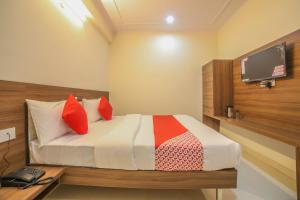a bedroom with a bed with red pillows and a tv at OYO Hotel Morgan in Jaipur