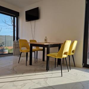 a dining room with a table and yellow chairs at Apartmani Relaxsea in Privlaka