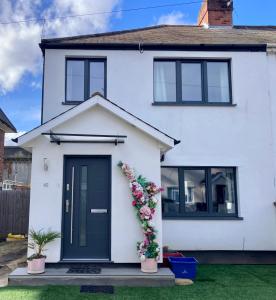 a white house with a black door and flowers at Cosy Modern Family Home Free Parking Garden in London