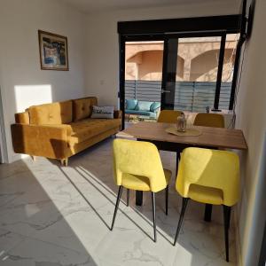 a living room with a table and yellow chairs at Apartmani Relaxsea in Privlaka