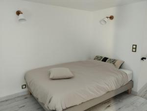 een bed in een kamer met witte muren en 2 verlichting bij Le Mont'aide Appartement jusqu'à 5 voyageurs - BAYEUX in Saint-Martin-des-Entrées