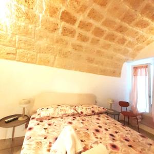 um quarto com uma cama grande e uma parede de tijolos em Palazzo Scianni Dimora della Petraia em Monopoli