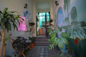 einen Flur mit Pflanzen und ein Neonschild an der Wand in der Unterkunft Art House Hostel Guadalajara in Guadalajara