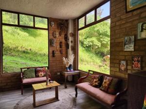 a living room with two couches and large windows at Hotel Pueblo del Mundo in Baños