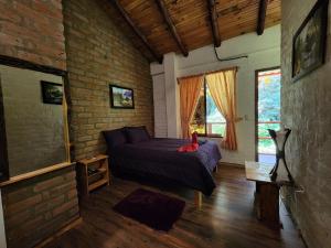 een slaapkamer met een bed en een bakstenen muur bij Hotel Pueblo del Mundo in Baños