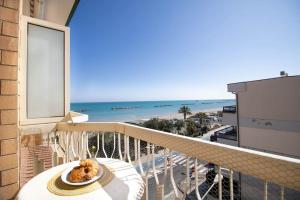 einen Balkon mit einem Teller Essen und dem Strand in der Unterkunft [Dimora Fronte Mare] Wi-Fi 7 posti Parcheggio in Porto San Giorgio