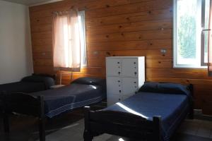 Duas camas num quarto com paredes e janelas de madeira em Folk Suites em El Calafate
