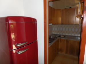 einen roten Kühlschrank in einer Küche neben einer Spüle in der Unterkunft Ferienhaus für 6 Personen ca 46 qm in Bibione, Adriaküste Italien Bibione und Umgebung in Bibione