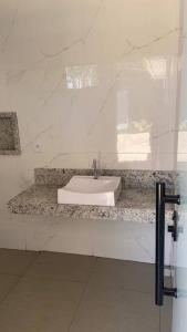 uma casa de banho com um lavatório branco num balcão de mármore em Sítio Gilmar2filhas em Sete Lagoas