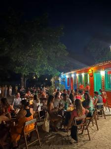 a crowd of people sitting at tables at night at Pousada Crocodilo Caraíva in Caraíva