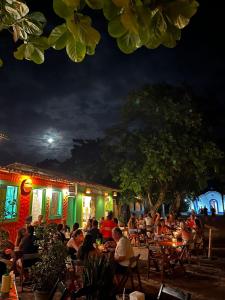 a group of people sitting outside a restaurant at night at Pousada Crocodilo Caraíva in Caraíva