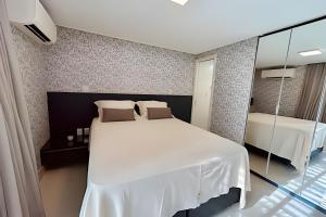 1 dormitorio con cama blanca y espejo en Incríveis apartamentos no Solar Tambaú, en João Pessoa