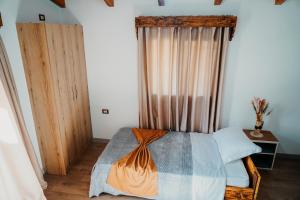 Schlafzimmer mit einem Bett und einem Fenster mit Vorhängen in der Unterkunft Bujtina ANLU in Gjirokastër