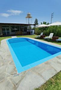 帕拉卡斯的住宿－Bungalow Sol del Sur，一座带椅子的蓝色游泳池和一座建筑