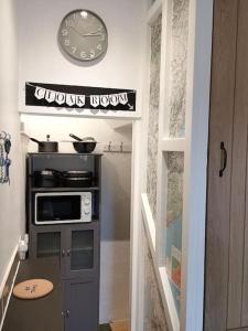 a kitchen with a stove and a clock on the wall at The Cobbles - Central, Parking, Netflix & Woodburner in Hebden Bridge
