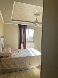 een slaapkamer met een bed voor een raam bij شقة فاخرة بالمنتزة فيو بحر ومنتزة in Alexandrië