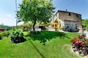 een oud stenen huis met een boom in een tuin bij Ferienhaus mit Privatpool für 4 Personen ca 90 qm in Lanciole, Toskana Provinz Pistoia in Lanciole