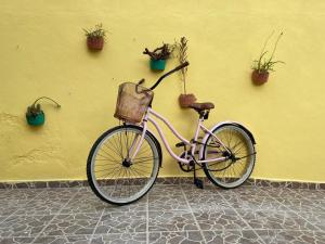 a pink bike parked next to a yellow wall with potted plants at Casa Kini en Cancún in Cancún