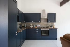 a kitchen with blue cabinets and a stove top oven at Cheltenham Cottage in Cirencester
