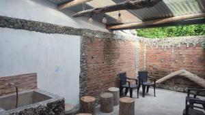 eine Terrasse mit Stühlen und einer Badewanne in einer Backsteinmauer in der Unterkunft Casa Rio de Cristal in Pijao