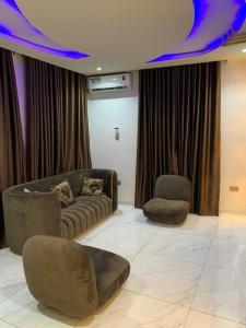Loft and Luxe Apartment في لاغوس: غرفة معيشة مع أريكة وكرسيين