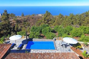 een luchtzicht op een zwembad met parasols en de oceaan bij Ferienhaus mit Privatpool für 4 Personen ca 85 qm in Tijarafe, La Palma Westküste von La Palma in Tijarafe