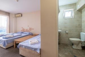 a bedroom with two beds and a bathroom with a toilet at Yubim rooms & free private parking in Sofia