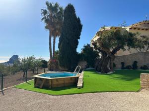 a swimming pool in a yard with trees and a house at Chalet Cucarres in Calpe