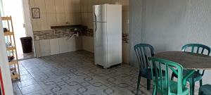 a kitchen with a table and a white refrigerator at Kitnet Região Central in Itapoa