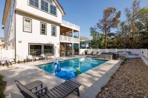 a pool with an inflatable dolphin in front of a house at Aurora 6 BR Elevator Theater Rec Room Pool & Hot in Corolla