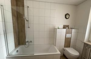 a bathroom with a tub and a toilet and a clock at Ferienwohnung zur Langen Meile in Kalteneggolsfeld