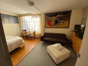 a bedroom with a bed and a couch and a tv at Casa Skema - Garden in Quito