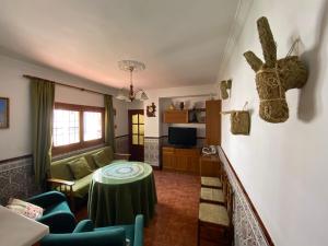Casa Virgen de Gracia في أرشذونة: غرفة معيشة مع طاولة وكراسي خضراء
