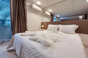 1 dormitorio con 1 cama blanca grande y ventana en Solar Tambaú Apartamentos Luxuosos, en João Pessoa