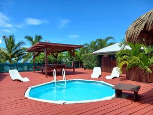 a swimming pool on a deck with a table and a bench at Pension LE PASSAGE vu mer in Vaitoare