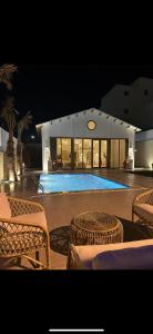 a swimming pool at night with chairs and a building at شاليه pali villa in Buraydah