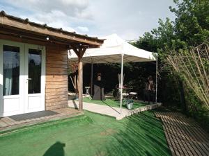 patio z białym parasolem i stołem w obiekcie CABANE, BUNGALOW, BULLE ET SPA LE REFUGE ZEN ET BIEN ETRE w mieście Montpouillan