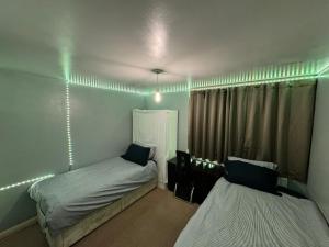two beds in a room with green lights at London gateway get-away in Hounslow