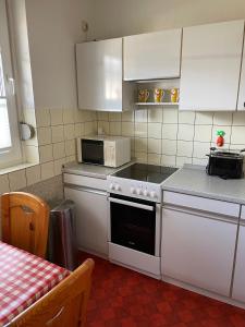 uma cozinha com armários brancos e um forno com placa de fogão em Ferienhaus "Vogelnest" em Berumbur