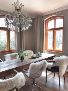 ein Esszimmer mit einem Tisch, Stühlen und einem Kronleuchter in der Unterkunft Landhaus Vogtland in Bad Elster