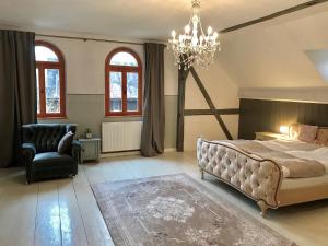 ein Schlafzimmer mit einem Bett, einem Stuhl und einem Kronleuchter in der Unterkunft Landhaus Vogtland in Bad Elster