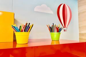 three cups on a shelf with pencils and a hot air balloon at Aptos modernos no Solar Tambaú - 1 e 2 Quartos in João Pessoa