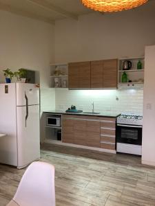a kitchen with a white refrigerator and wooden cabinets at 1991HospedajeD3 in Ensenada