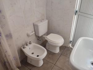 a white bathroom with a toilet and a sink at Casa de Alquiler in Corrientes