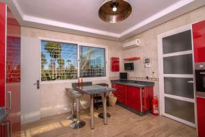 a kitchen with red cabinets and a table and a window at Villa Meriem, Fès in Oulad Tayeb