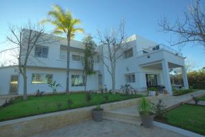 une maison blanche avec des palmiers devant elle dans l'établissement Villa Meriem, Fès, à Oulad Tayeb