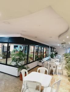 a restaurant with white tables and white chairs at Hotel Bolivariano AV in Ibagué