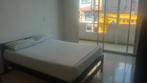 łóżko w pokoju z dużym oknem w obiekcie Hotel Bolivariano AV w mieście Ibagué