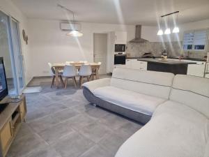 a living room with a white couch and a kitchen at La Maison de Coco in Le Puy